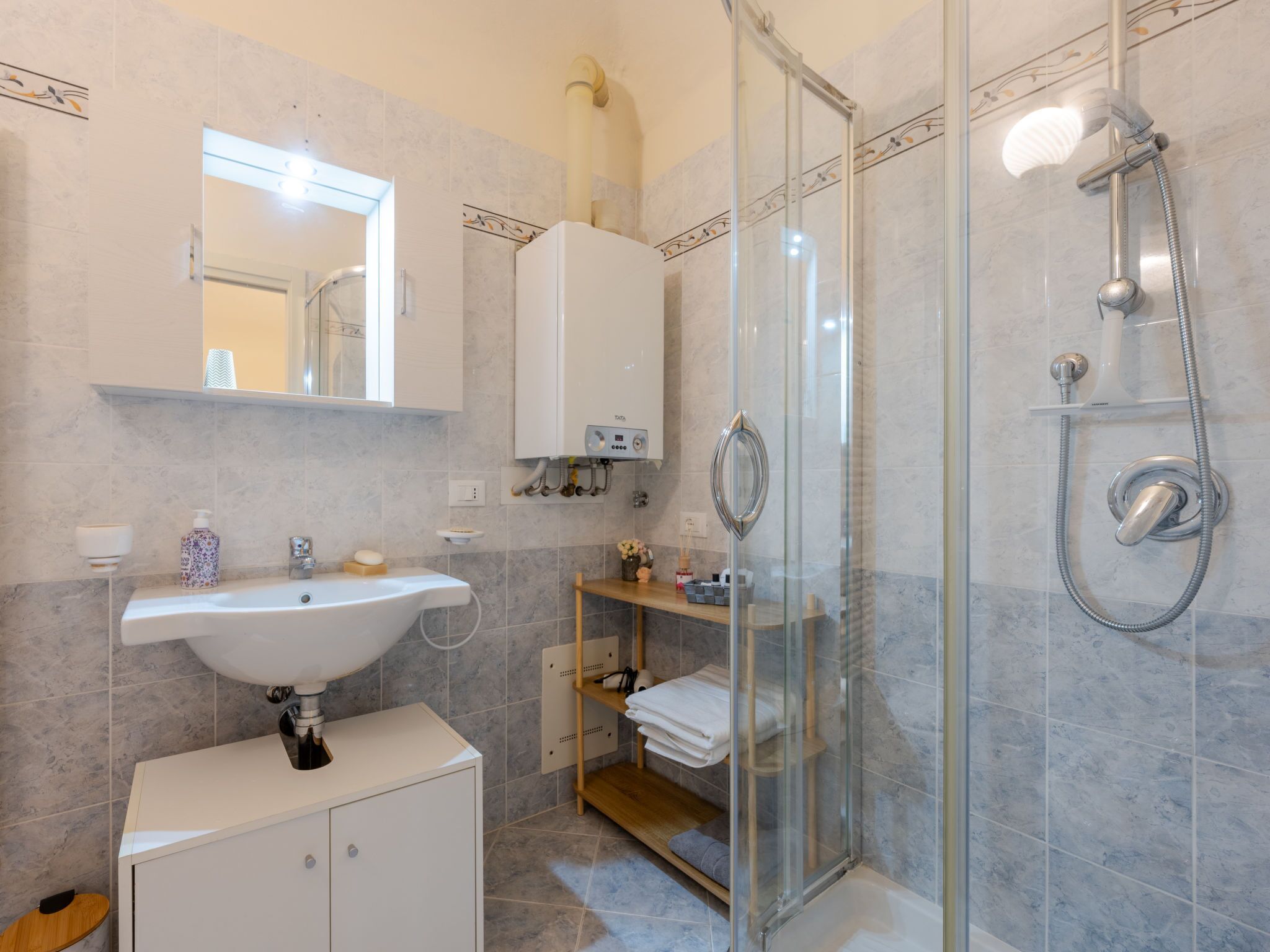 Un baño moderno con ducha de vidrio, un lavabo blanco y un espejo sobre el lavabo.