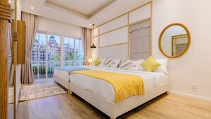 A bedroom with a large bed, a view of a building through a glass door, and a mirror on the wall.