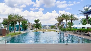 A swimming pool area with palm trees, a wooden deck, and a sign indicating no diving.