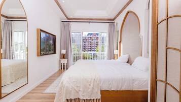 A bedroom with a large bed, a mirror, a window with curtains, and a view of a building outside.
