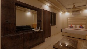 Een hotelkamer met een grote spiegel, een houten kaptafel, een bed met decoratieve kussens en een plafondventilator.