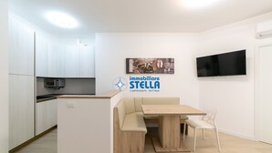 Una cucina moderna con mobili bianchi, un forno a microonde integrato e un'isola in legno con posti a sedere.