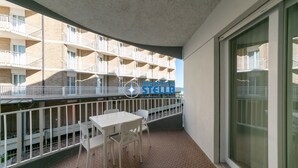 Un balcone con tavolo e sedie, vista su un edificio con balconi e un cartello con le scritte 'immobilier' e 'stella'.