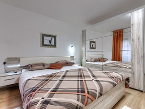 A modern bedroom with a large bed, a bedside table, a mirror, and a wall-mounted light.