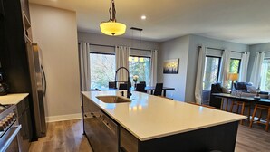A modern kitchen with a central island, stainless steel appliances, and pendant lighting.