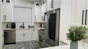 A modern kitchen with white cabinets, stainless steel appliances, and a marble countertop. - Modern Mountain Escape | Cozy Retreat with Stunning Views (Eden)