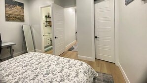 A bedroom with a bed, a door, a mirror, and a painting on the wall. - Modern Mountain Escape | Cozy Retreat with Stunning Views (Eden)