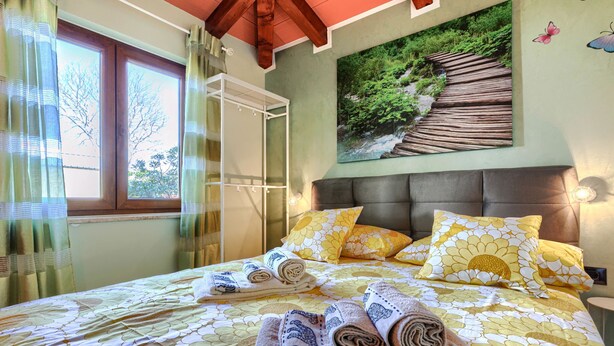 A bedroom with a bed, pillows, and a painting of a forest scene.
