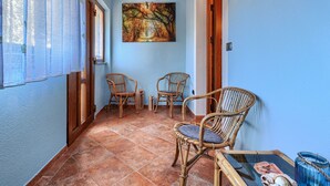 A corridor with tiled flooring, wooden beams, and two wicker chairs.
