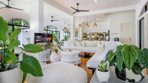 A spacious living area with a white sofa, round coffee table, and large potted plants. - Homey 5 BR Villa In Seminyak (Seminyak)
