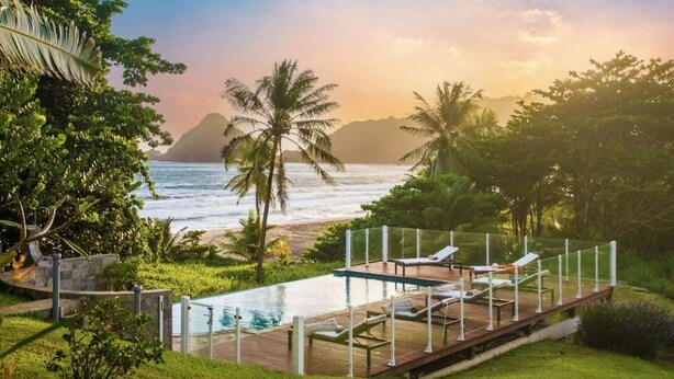 A pool area with lounge chairs, a wooden deck, and a view of the ocean and mountains. - F2 M'Bay : Sea & Pool access (Anse Charpentier)