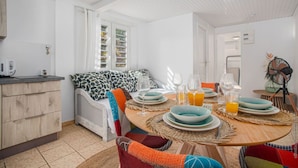 A bright, well-lit dining area with a round table set for two, featuring plates, glasses, and a jug of orange juice. - F2 M'Bay : Sea & Pool access (Anse Charpentier)