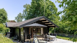 Eine Holzhütte mit einer Terrasse, ausgestattet mit Gartenmöbeln und einem Tisch.