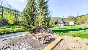 A wooden bench in a landscaped area with a stone pathway and a pile of firewood. - Dolní Lysečiny by Interhome (Horní Maršov/Pec pod Sněžkou)