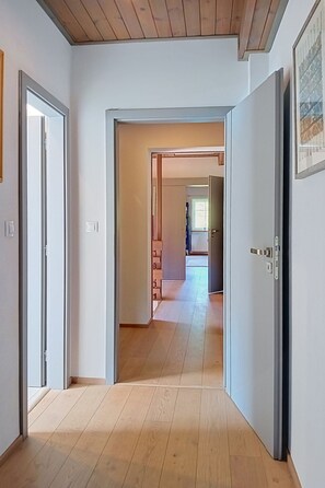 Een gang met houten vloer die leidt naar een kamer met een deur.