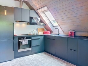 Una cucina compatta con forno integrato, microonde e un piccolo piano di lavoro.