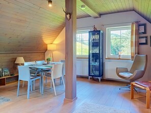 A dining area with a table and chairs, a tall cabinet with glassware, a window with a view of trees, and a wooden ceiling. - Dolní Lysečiny by Interhome (Horní Maršov/Pec pod Sněžkou)