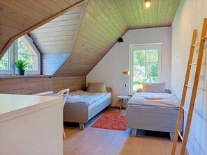 A bedroom with a sloped ceiling, two beds, a small table, and a window with a view of greenery. - Dolní Lysečiny by Interhome (Horní Maršov/Pec pod Sněžkou)