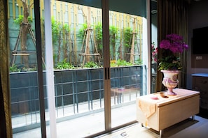 Enjoy the serene views from your balcony with a sliding glass door, featuring lush greenery and a beautiful vase with fresh flowers.