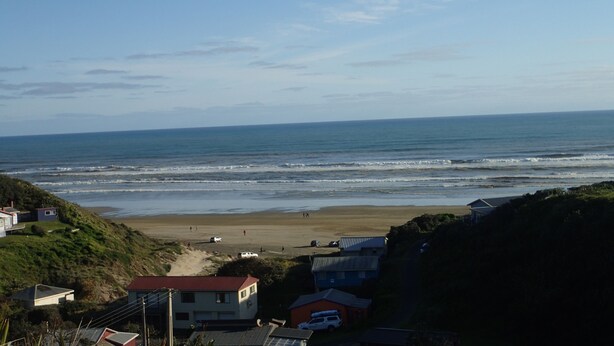 Vista costera con playa, casas y cielo despejado.