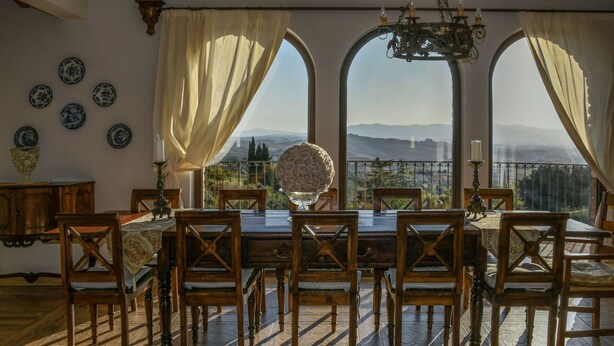 A dining room with a table set for six, large windows with curtains, and a view of the countryside. - Villa Torresassa - Villa with pool near Montaione, Tuscany (Iano)