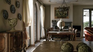 A dining room with a wooden table, chairs, a chandelier, and decorative plates on the wall. - Villa Torresassa - Villa with pool near Montaione, Tuscany (Iano)