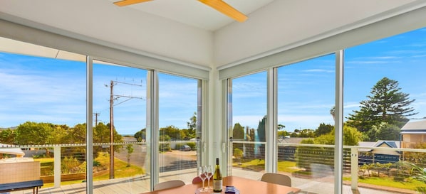 A modern room with large windows, a wooden ceiling, and a table with a bottle and glasses.