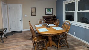 Un comedor con una mesa y sillas de madera, un piano y una ventana con persianas.