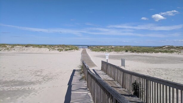 A wooden boardwalk leading to a beach with dunes and a clear sky. - Charming 3-Bedroom Wildwood Crest Spot: Beach, Bay, and Boardwalk- all so close! (Wildwood)