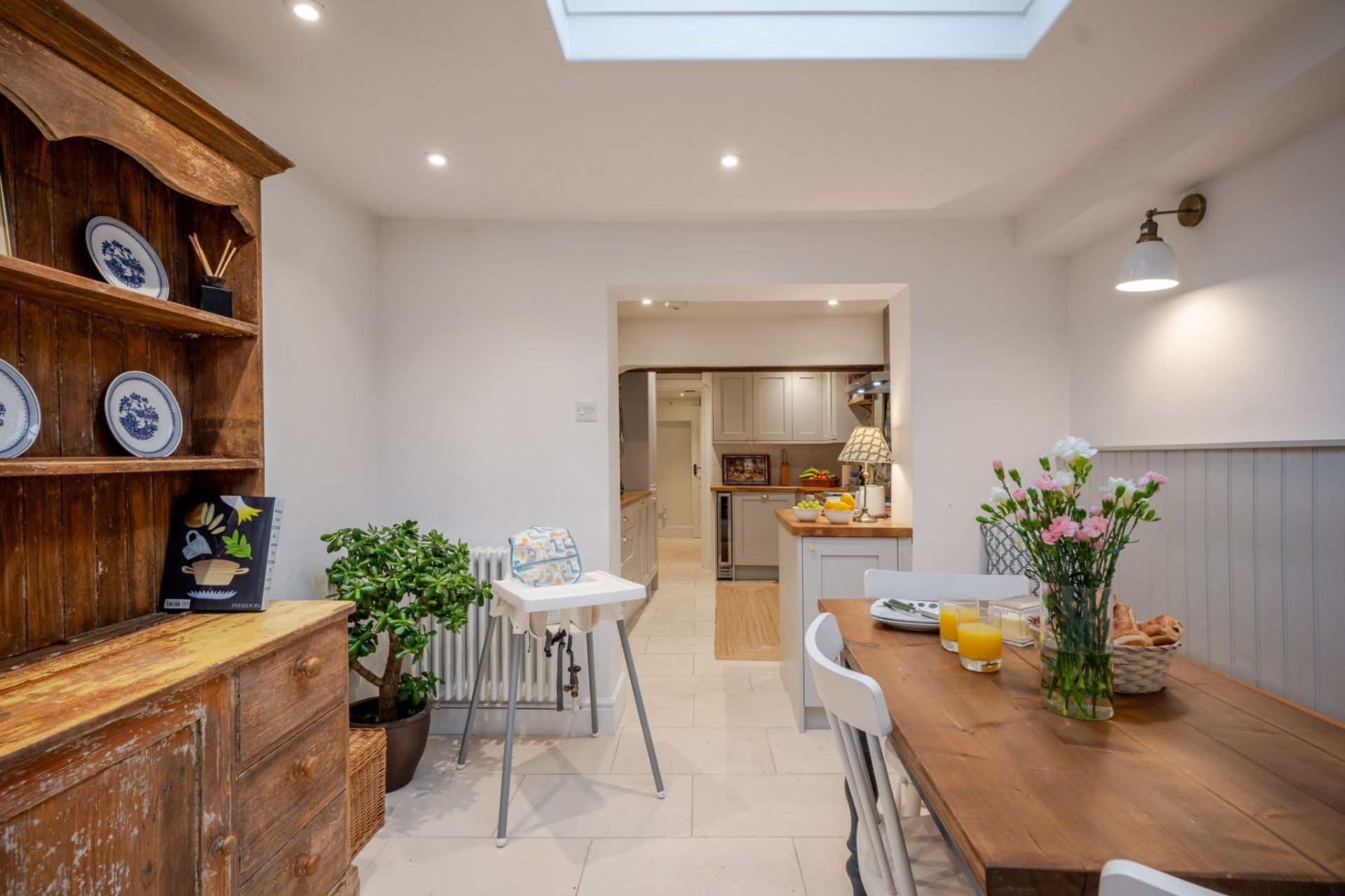 A modern kitchen with a wooden countertop, a dining table with chairs, and a view into the adjacent dining area.