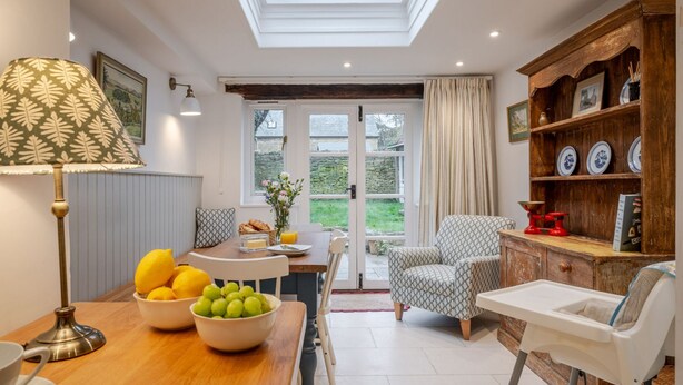 A cozy dining area with a table set for breakfast, a comfortable armchair, and a high ceiling with skylights. - Beautifully presented holiday cottage - Stonecrop Cottage (Moreton-in-Marsh)