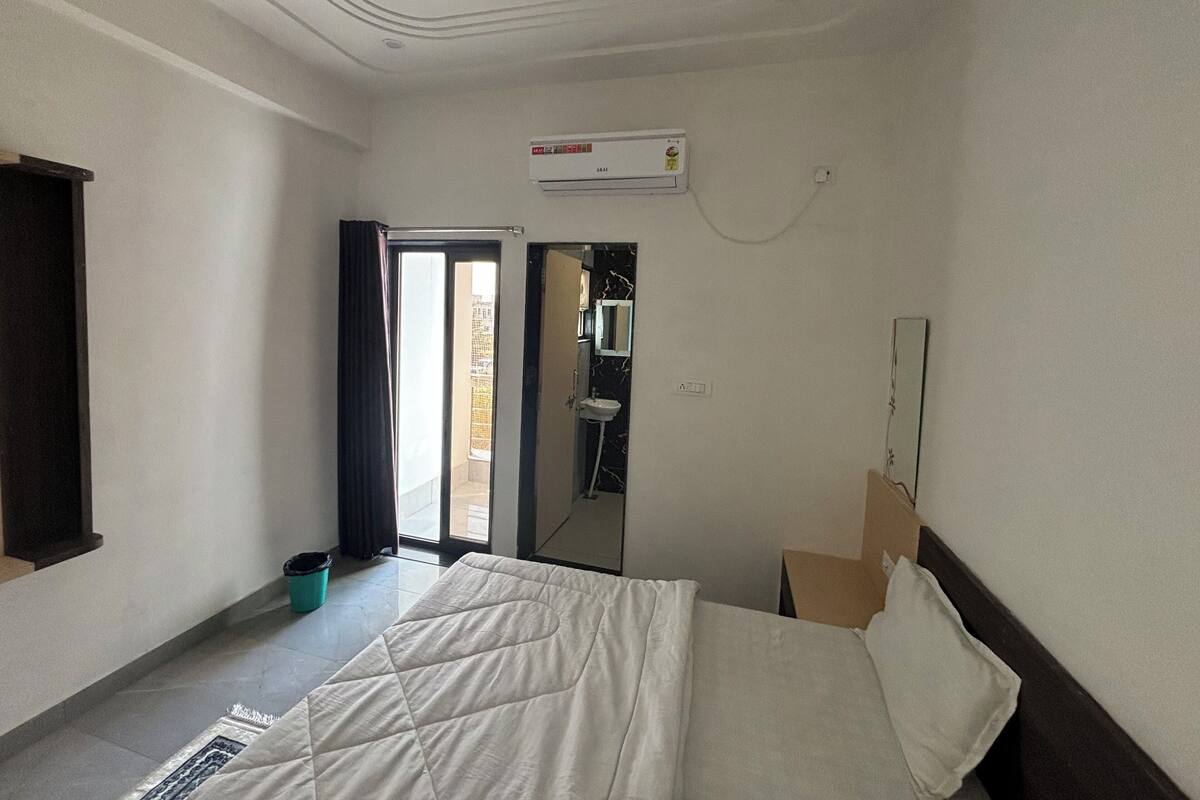 Una habitación de hotel con cama, un baño con espejo y un equipo de aire acondicionado.