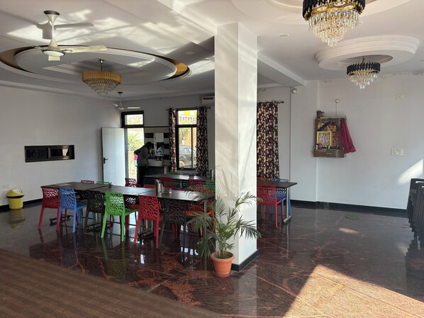 Una habitación amplia con un ventilador de techo moderno, una araña y un comedor con sillas de colores.
