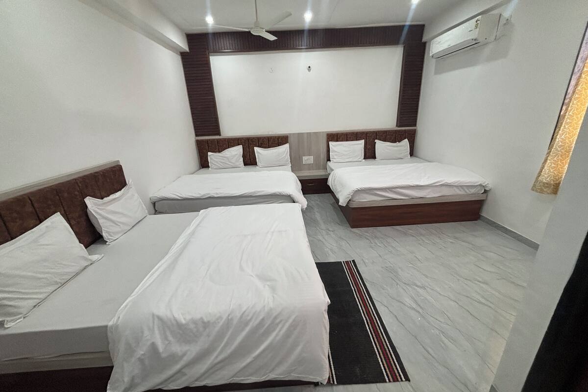 Habitación de hotel con tres camas individuales, ventilador de techo y aire acondicionado.
