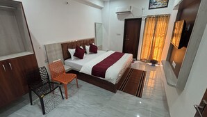 A hotel room with a bed, a chair, a wardrobe, and a ceiling fan. - Shree Radhe Mohan Hotel and Resort (Danta Ramgarh)
