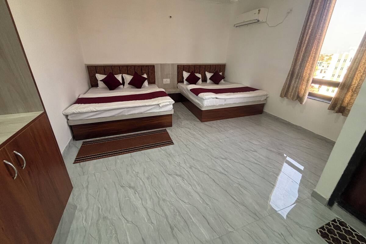 Habitación de hotel con dos camas, cabecero de madera, suelo de mármol y ventana con cortinas.