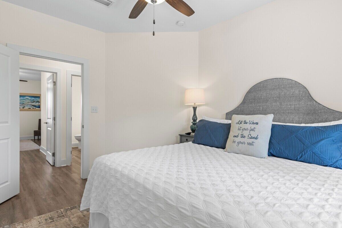 A bedroom with a bed, a nightstand, a lamp, and a ceiling fan.