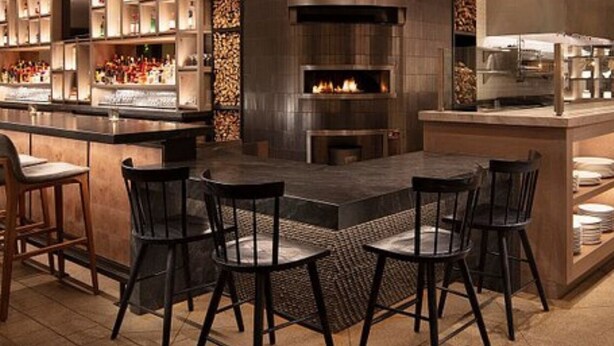 A modern kitchen with a central island, bar stools, and a display of kitchenware. - The Curated Haven, by Vinifera Homes (Sonoma)