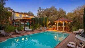 A swimming pool with lounge chairs, a gazebo, and a house in the background. - The Curated Haven, by Vinifera Homes (Sonoma)