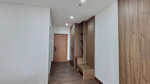 A hallway with wooden flooring, white walls, and built-in wooden shelving units. - TCICO Hotel (Phan Dinh Phung)