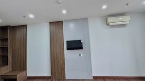 A room with a built-in wooden shelf, a mounted TV, and an air conditioning unit. - TCICO Hotel (Phan Dinh Phung)