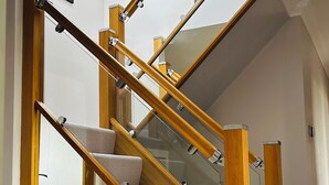 Eine moderne Treppe mit Holzhandläufen und Glasfeldern, die zu einer oberen Etage führt.