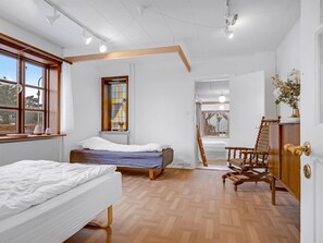 Un dormitorio con dos camas, una silla de madera, un radiador y una ventana con vistas.