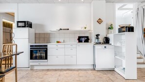 Une cuisine moderne avec des meubles blancs, un four à micro-ondes, un four traditionnel et un lave-vaisselle.