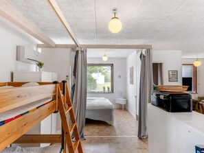 Ein modernes, helles Zimmer mit einem Stockbett, einer Halterung, einem Schreibtisch mit Korb und einem Fenster mit Vorhängen.