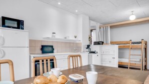 Une cuisine moderne avec une table à manger, des chaises, un four à micro-ondes et un lit superposé.