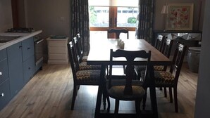A dining area with a wooden table and chairs, a kitchen area with cabinets, and a view through the window. - Studio Apartment sleeps up to 4 guests in Kinvara (Cappaghmore)