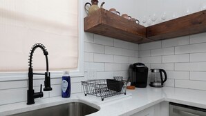 A kitchen with a stainless steel sink, a coffee maker, and a dish rack. - 69 Unit- B (Cartersville)