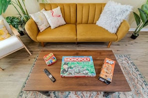 Un salon avec un canapé, une table basse sur laquelle sont posés des jeux de société et une télécommande.