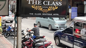 A sign for 'The Class Boutique Hotel' with a clear view of the surrounding street and parked vehicles. - The Class Boutique Hotel (Pattaya)